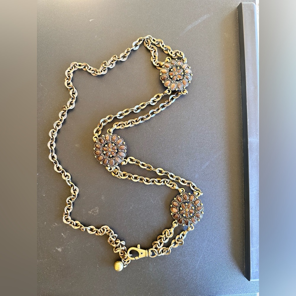 Brass tone flower belt with brown rims tones. Lobster clasp closure.
